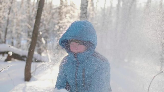 A child plays in the winter outdoors, runs, throws snow to the top. Active outdoor sports