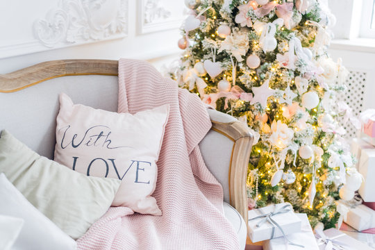 Christmas or new year decoration at Living room interior and holiday home decor concept. Calm image of blanket on a vintage sofa with tree, lifghts, gifts. Selective focus