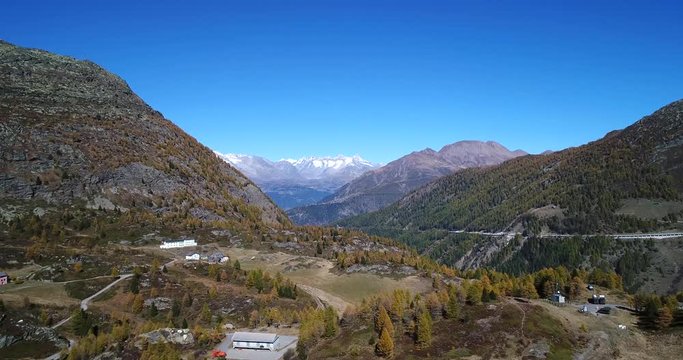 Alpine landscape, Cinema 4k aerial view over the top of simplon pass and towards snowy mountains, on a sunny autumn day, in Valais, in the alps of Switzerland