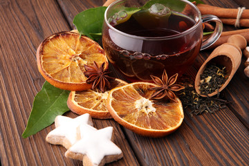 Christmas hot tea with spices and cookies on wooden table.