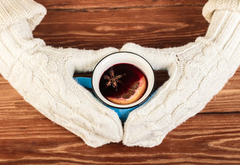 hands in gloves holding mulled wine