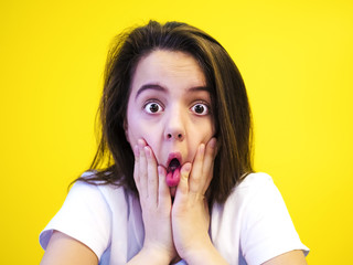 Portrait of surprised girl covering her mouth looking at the camera with stunned and shocked face expression while listening to some sensational news during conversation with her friend