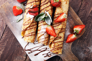 Crepes with jam, berries and sugar powder. Homemade pancakes, delicious breakfast.