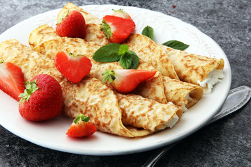 Crepes with jam, berries and sugar powder. Homemade pancakes, delicious breakfast.