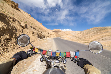 Motorcycling the Srinagar Leh Highway, a high altitude road that traverses the great Himalayan range, Ladakh, India. Mans hands on the helm of the Royal Enfield motorcycle.