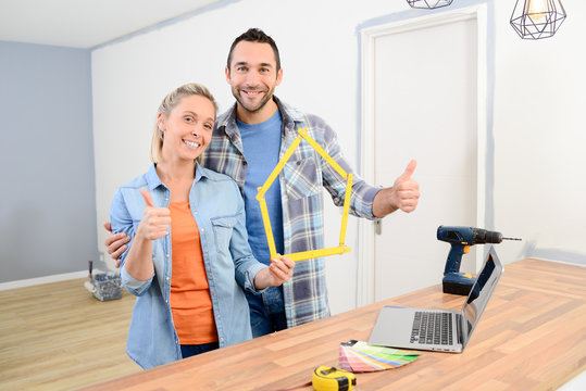 cheerful young couple making future project and renovating new home thumbs up
