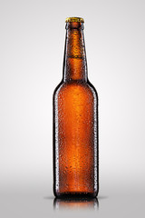 Bottle of beer with drops on gray background.