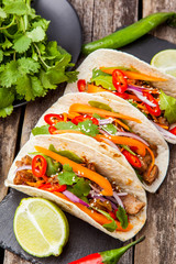 Three mexican tacos with meat and vegetables. Tacos al pastor on wooden dark background.