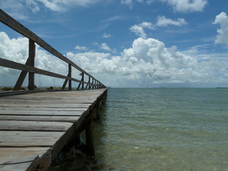 Wooden pier, and calm seas, blue sky and white clouds, on the Gulf of Mexico.