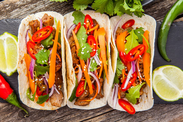 Three mexican tacos with meat and vegetables. Tacos al pastor on