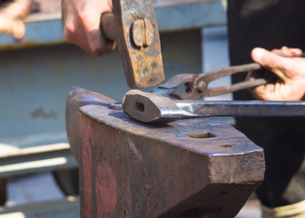 blacksmith performs the forging of hot glowing metal on the anvil