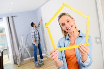 cheerful young love couple in new house painting and decorating their home wall