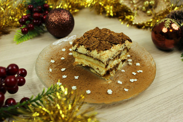 Obraz na płótnie Canvas Cake tiramisu on a plate close-up in a cut on a wooden background with Christmas decorations