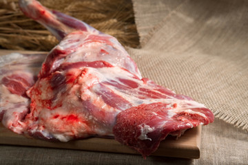 fresh meat, a leg of mutton on a cutting Board on a background of linen burlap