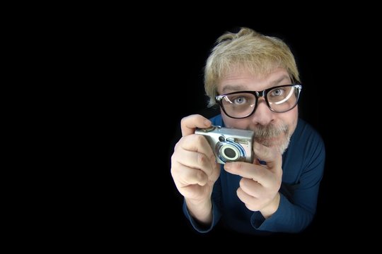 Nerd Fotograf mit alter Kamera schaut in die Kamera - Isoliert auf schwarz 