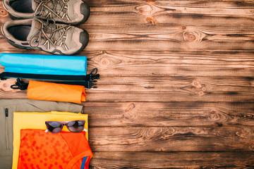 journey preparations concept with sunglasses, clothes and accessories on an brown wooden table. Top...