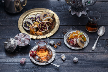 Cup of Turkish tea on saucer on rustic wood with snow in front of a dark blurred background with red and golden bokeh lights, copy space, selected focus, narrow depth of field