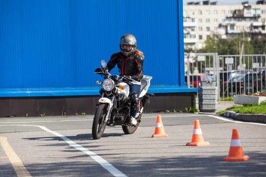 Fototapeta Woman L-driver driving slalom through the cones on training ground on motorcycle