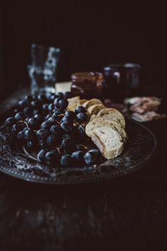 Red grapes and slices of bread on old fashioned silver plate