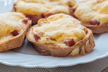 close-up of baked hot sandwiches with cheese and sausage on white plate