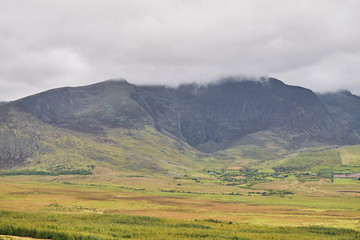 Fototapeta premium Distant view of clouds over mountain in a beautiful landscape. Ring of Kerry, Ireland.
