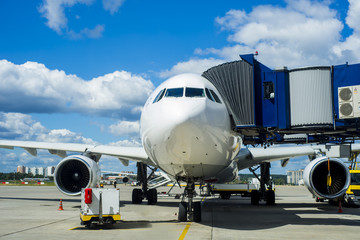 Modern white passenger airplane standing on parking place and get ready for boarding passengers in...
