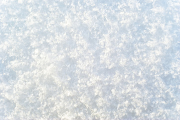background, texture - a bright white surface of freshly fallen snow, consisting of distinguishable individual snowflakes
