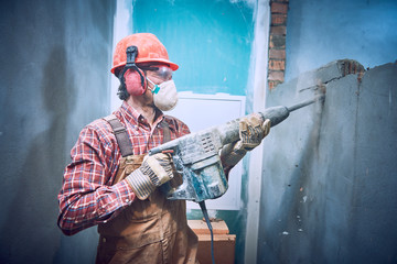 builder with hammer breaking wall indoors