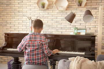 Little African-American boy playing piano indoors