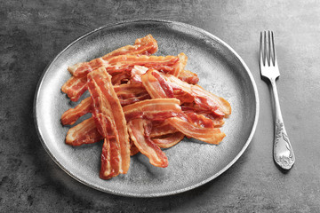 Plate with cooked bacon rashers on table