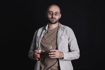 Drunk man with bottle of whiskey and glass on dark background. Alcoholism concept