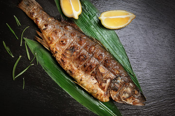 Tasty grilled fish on dark background