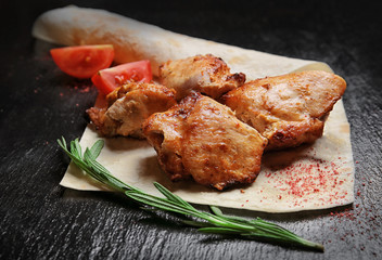 Tasty flatbread with pieces of shish-kebab on dark background