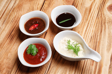 Bowls with tasty Asian sauces on wooden table