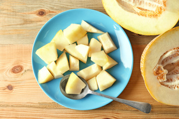 Plate with yummy melon on wooden table