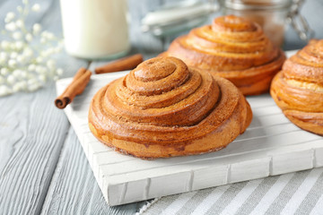 Wooden board with sweet cinnamon rolls on table