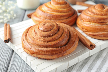 Wooden board with sweet cinnamon rolls on table
