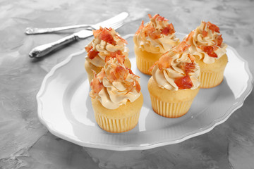 Tasty cupcakes with bacon on plate