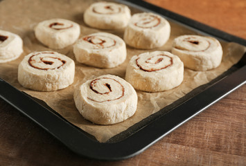 Baking sheet with raw cinnamon buns on table