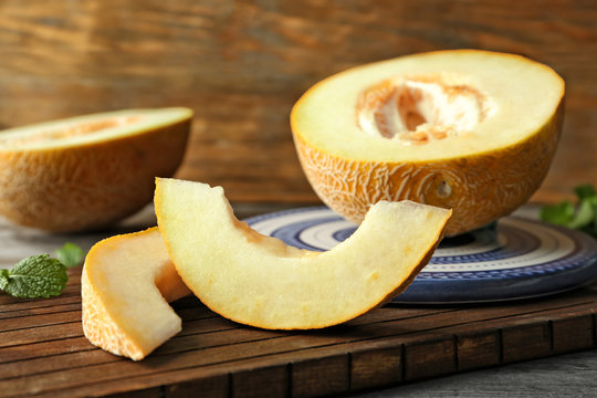 Wooden board with yummy melon slices on table