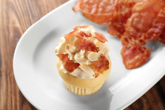 Tasty cupcake with bacon on plate