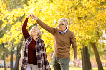Cute elderly couple dancing in autumn park