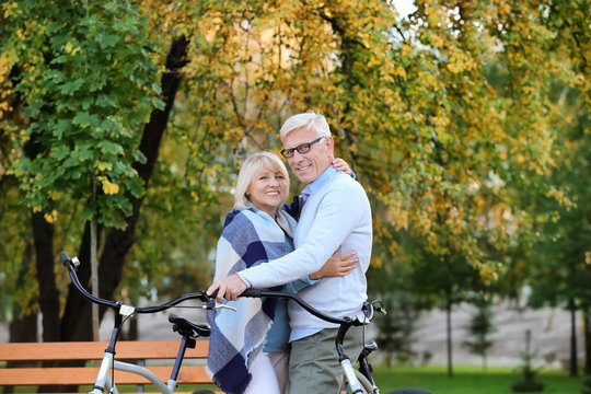 Cute elderly couple with bicycles in autumn park