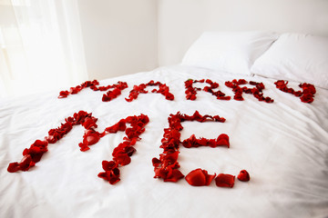 Message MARRY ME made of rose petals on bed in room