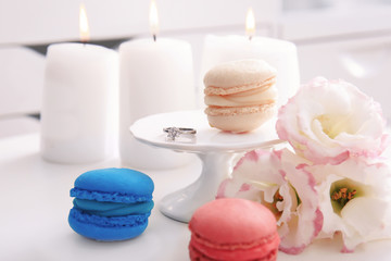 Beautiful composition with engagement ring, macarons and flowers on table