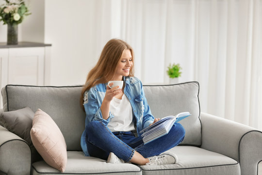 Beautiful woman reading book while resting on sofa at home