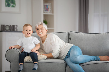 Attractive young mother with her baby on couch at home