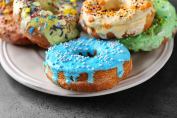Plate with yummy colorful donuts on grey background