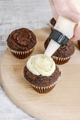 Woman prepares muffins decorated with fresh fruits.