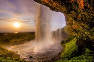 Incredible perspective behind a waterfall during sunset in Iceland. Colorful impression of...